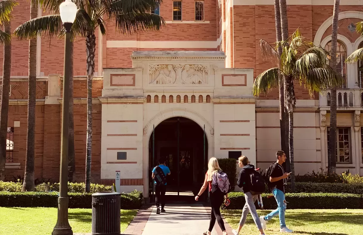 People walking outside of exterior of old grand university building