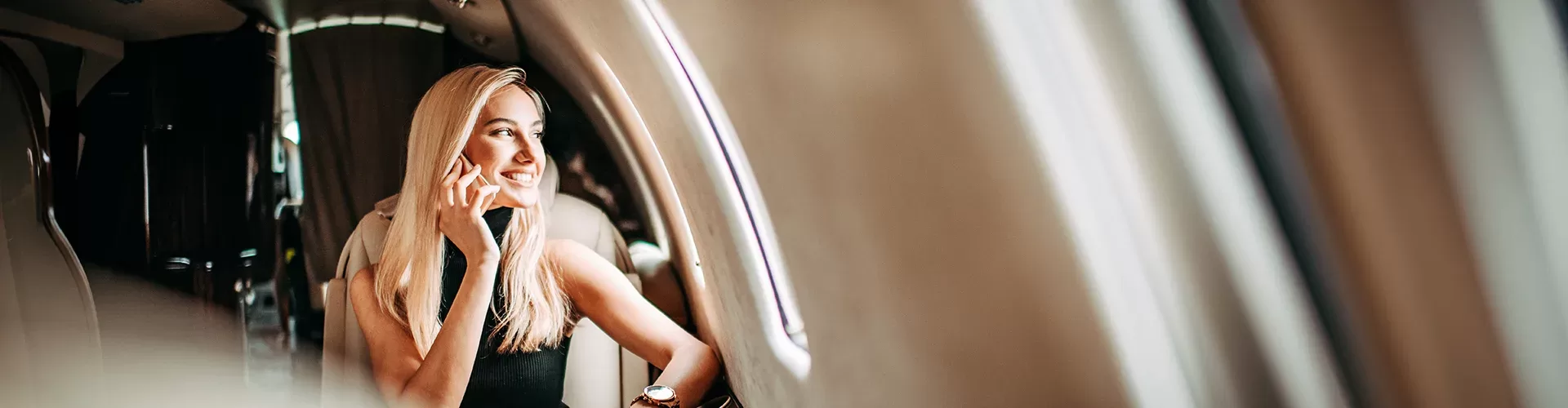A woman engaged in a phone conversation while seated inside a luxurious private jet.