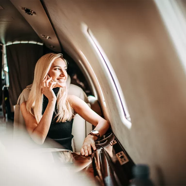 A woman engaged in a phone conversation while seated inside a luxurious private jet.