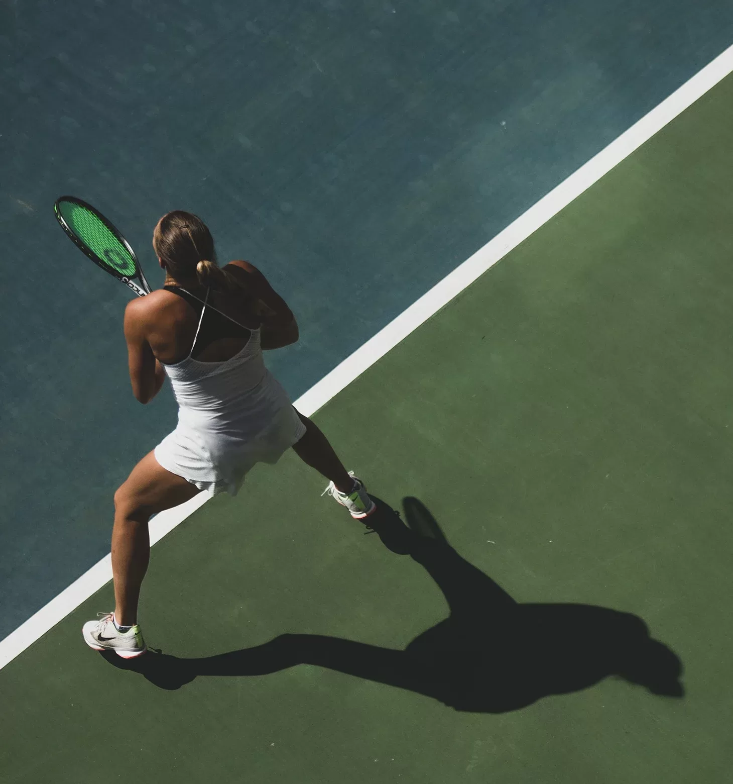 Women holding tennis racket placing tennis on a court