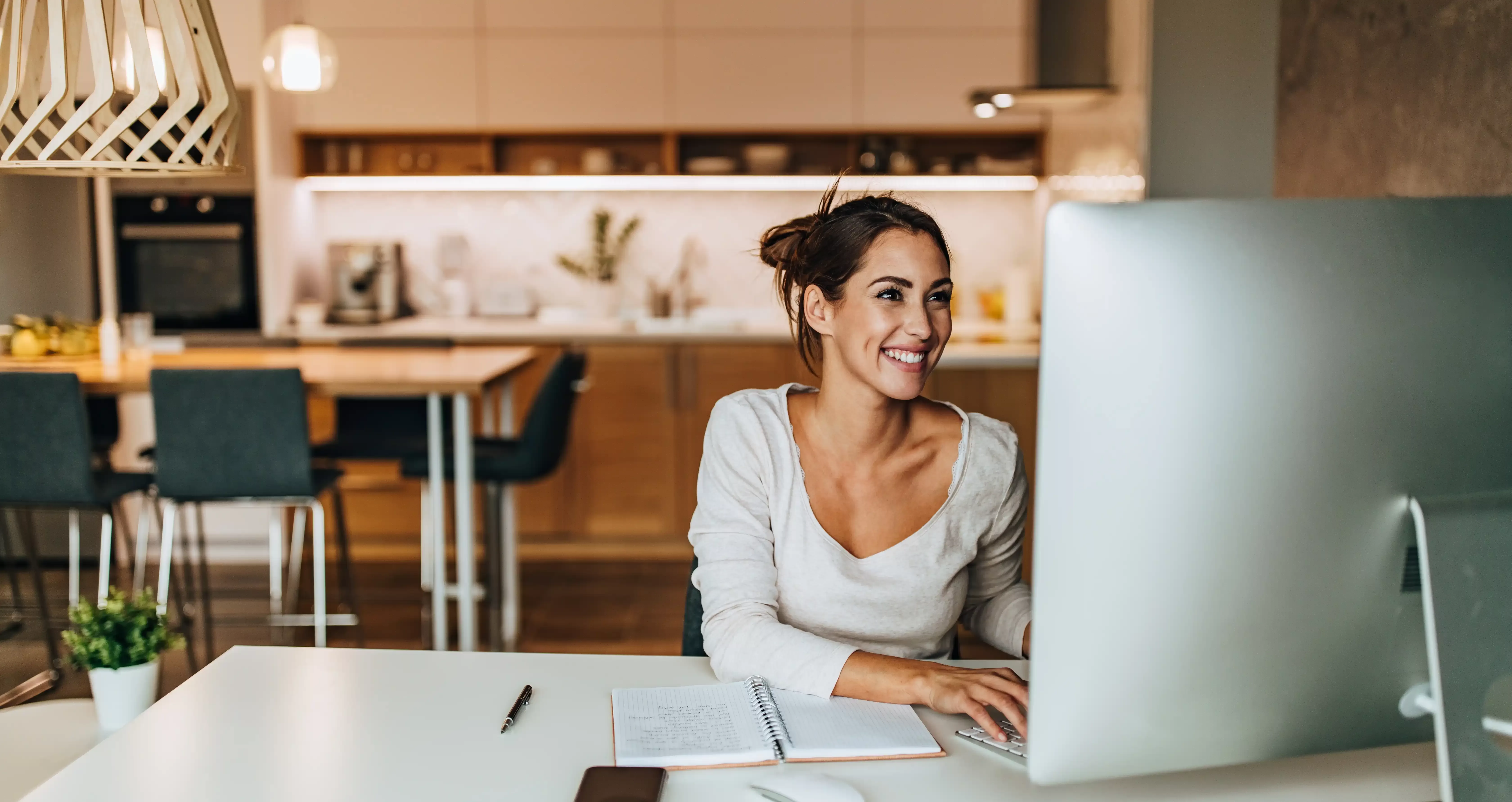 Women smiling on a Mac computer in a chic kitchen and office area