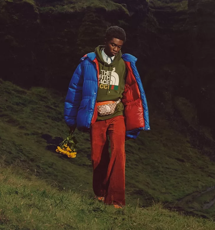Male model in North Face x Gucci fashion clothing walking down grass catwalk