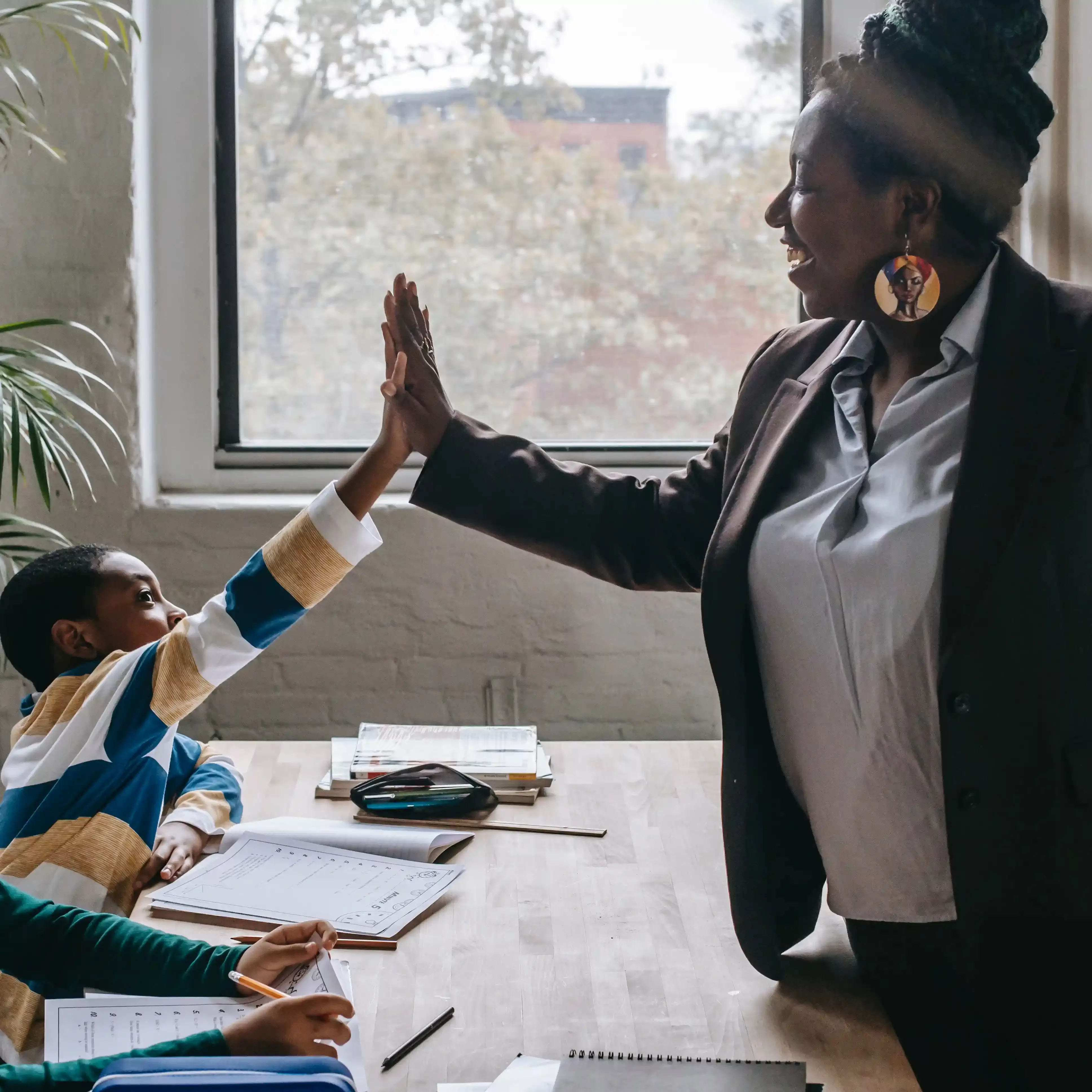Teacher and student high fiving over desk