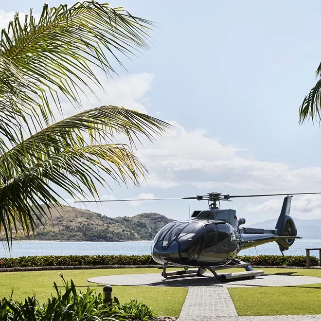 Luxury black helicopter on a brick landing pad on the land of qualia, Australia with a view of sea and hills.