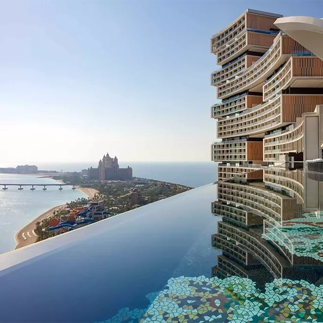 Infinity pool next to beautiful building hotel overlooking Dubai sea and view.