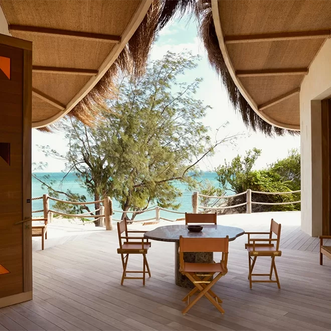 Dining table and chairs under straw thatched roof with sea view at Kisawa Sanctuary, Mozambique.