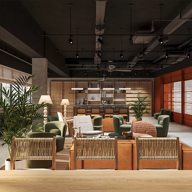 A modern, stylish co-working space with wooden tables, green and brown seating, and leafy plants. The ceiling features exposed ductwork and track lighting. Large windows allow natural light to fill the room, creating a warm and inviting atmosphere at Alma House, Singapore.