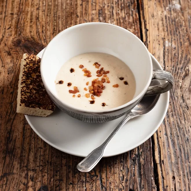 Onion soup served in a white bowl and spoon.