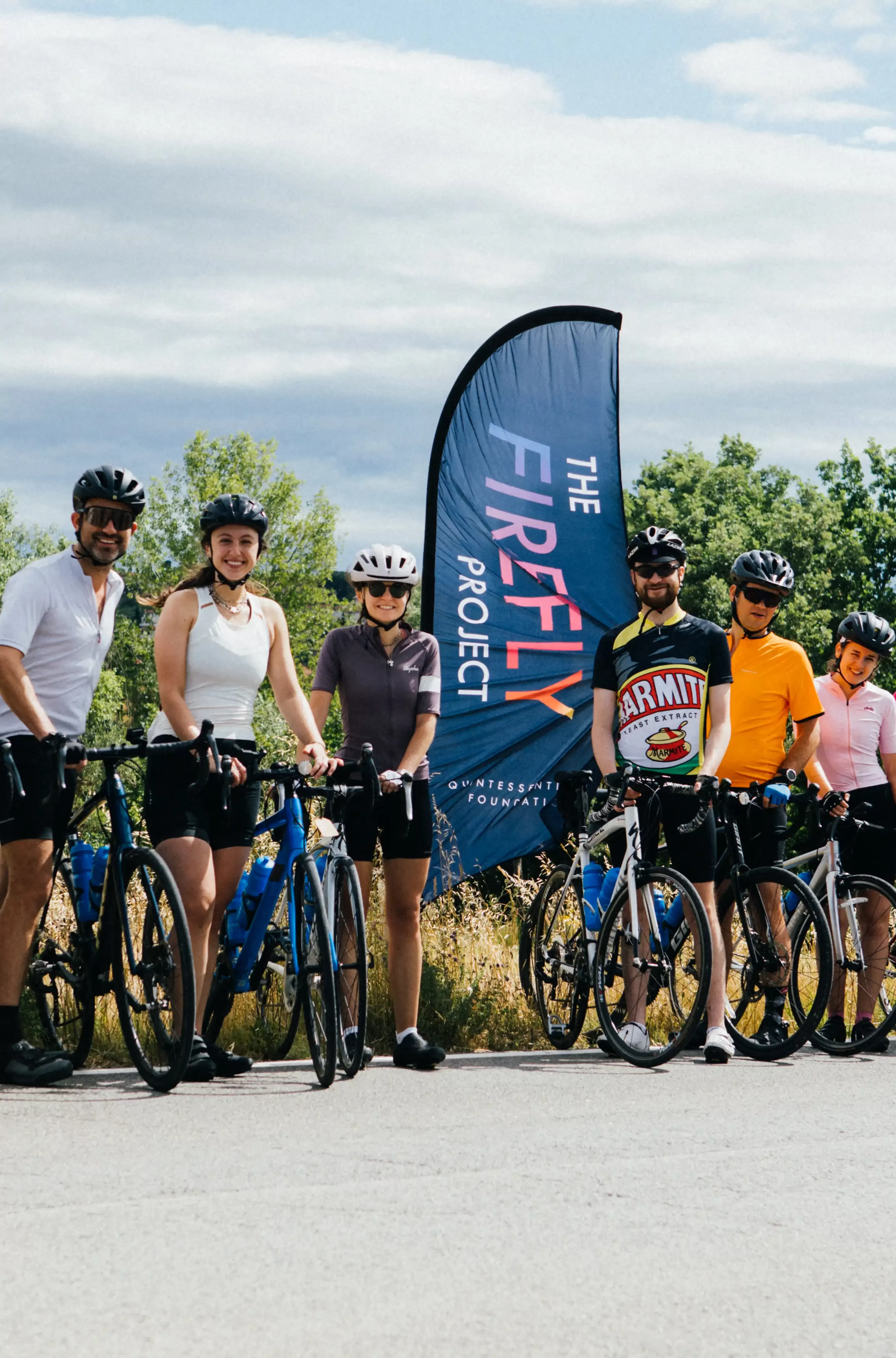 Quintessentially Foundation | The Firefly Project | Group of people in cycling gear with bikes posing for a photo