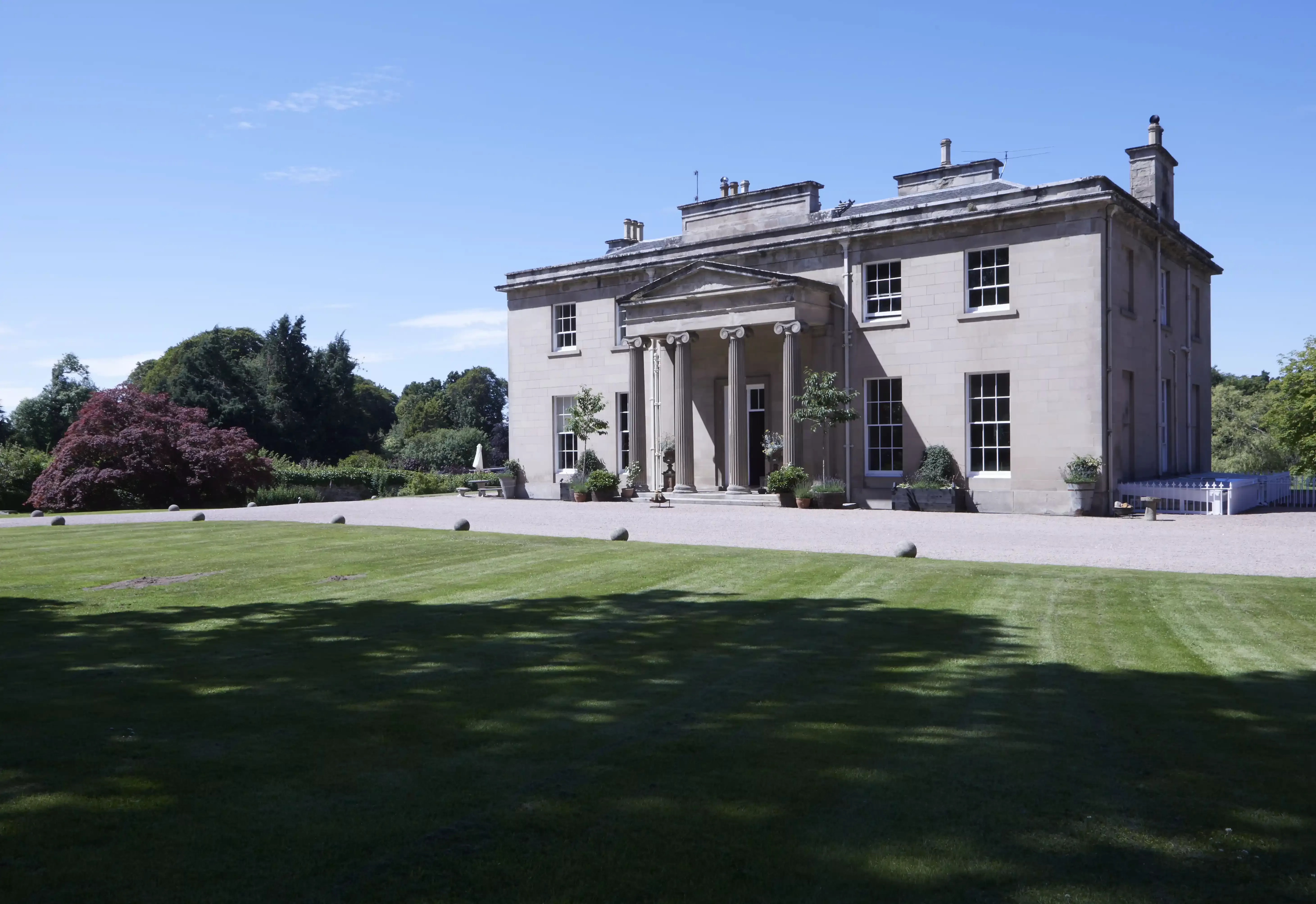 Grand white building exterior with cut grass outside Boath House, Nairn