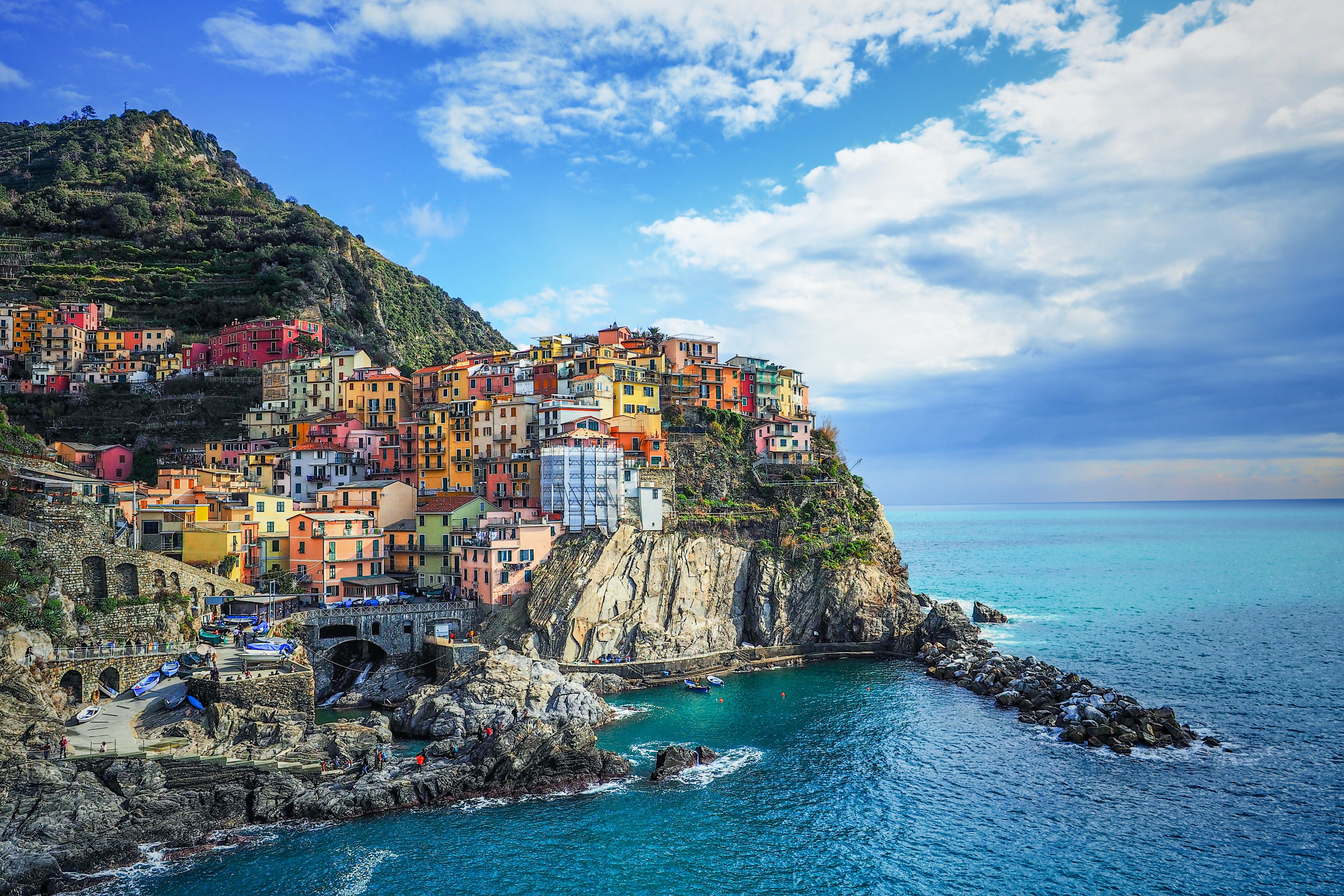 Colourful village houses built up on cliff edge of mountain next to the sea.
