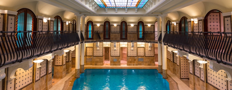 Beautiful horse shoe shaped room with balcony's over looking large blue swimming pool at Corinthia Spa, Budapest