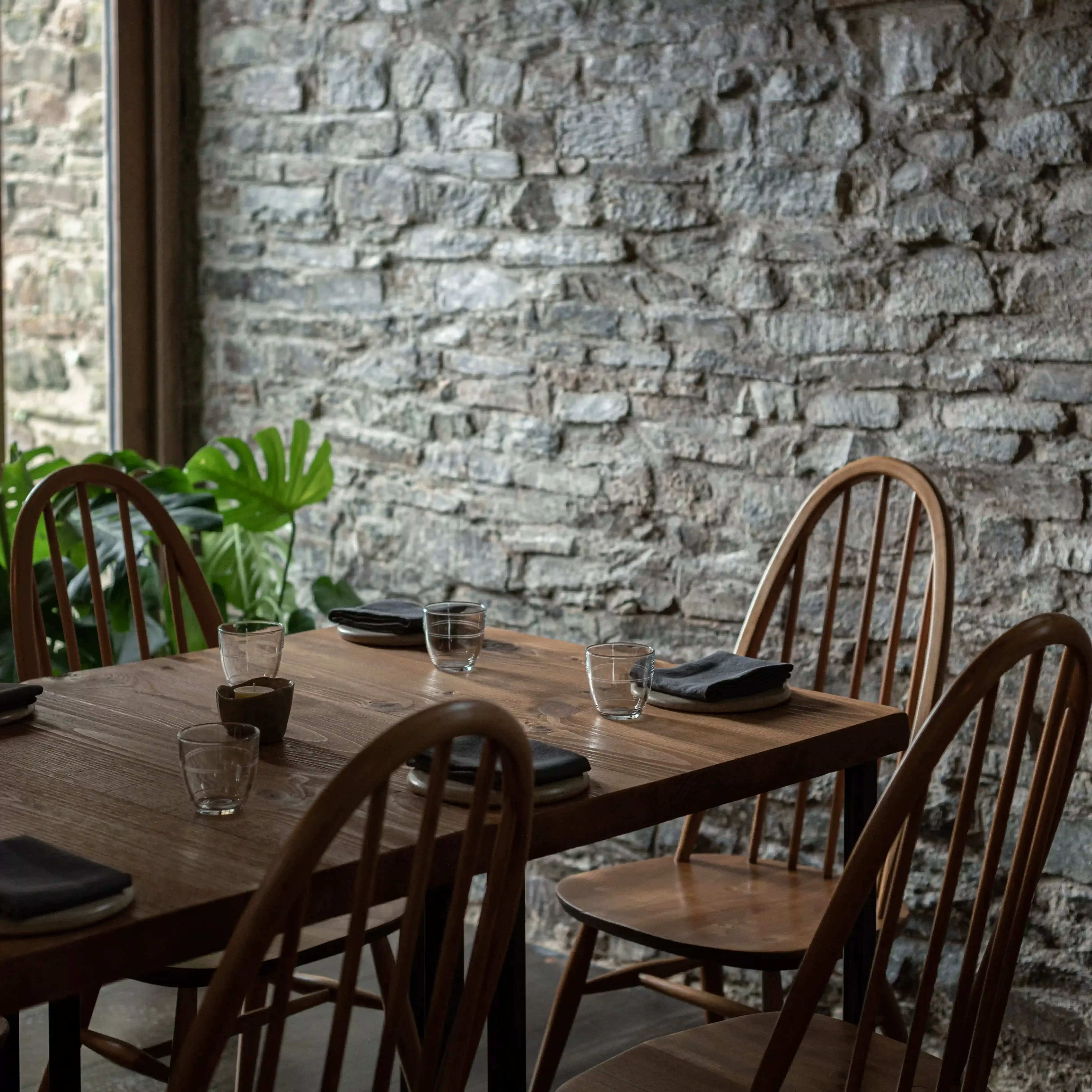 Set wooden table in front of Cornish stone exposed walls at Crocadon Farm, Cornwall