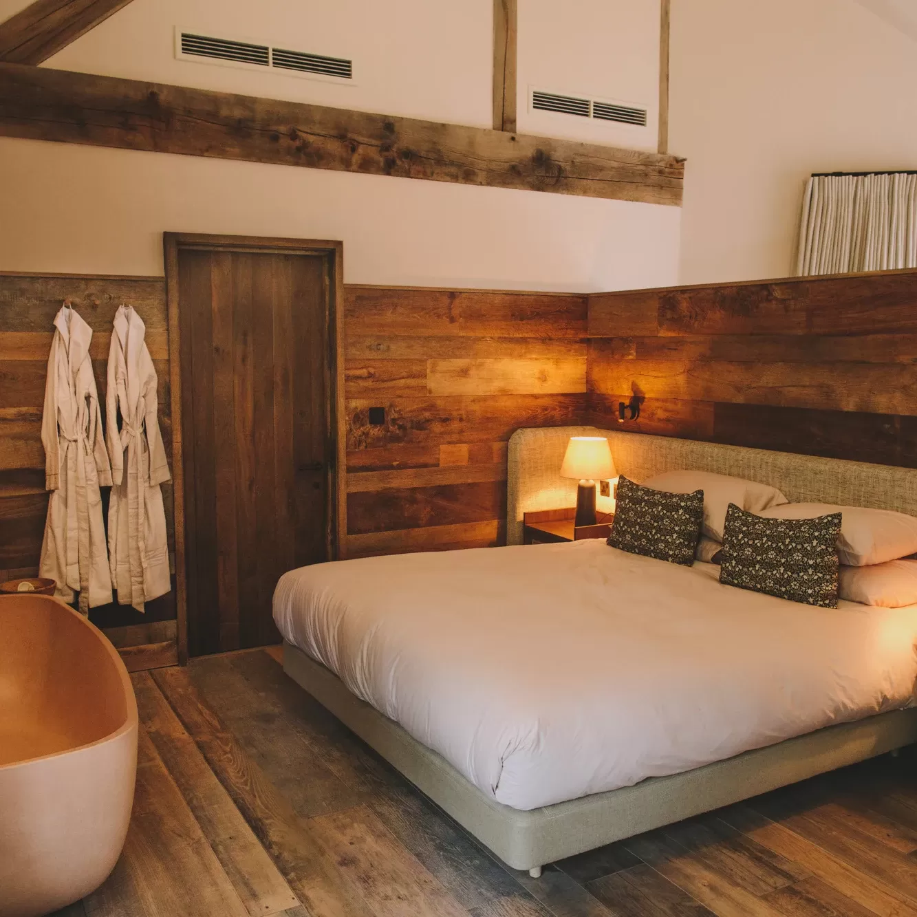 Luxurious wooden hotel room and comfy bed with hanging robes at Grace & Savour, The Weaver hotel
