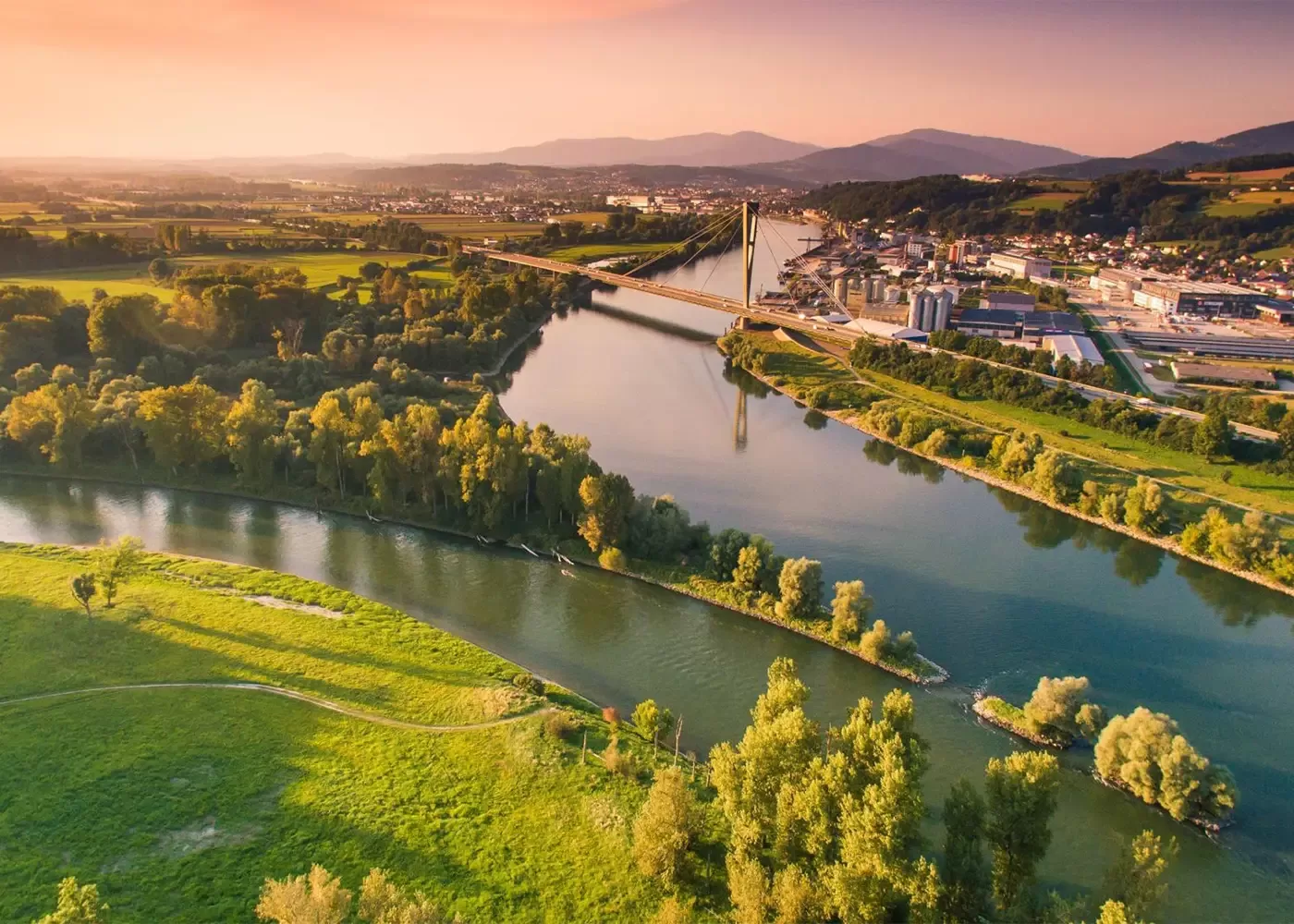Stunning aerial view of the Isar River near Munich, showcasing lush greenery and scenic landscapes under a vibrant sunset sky.