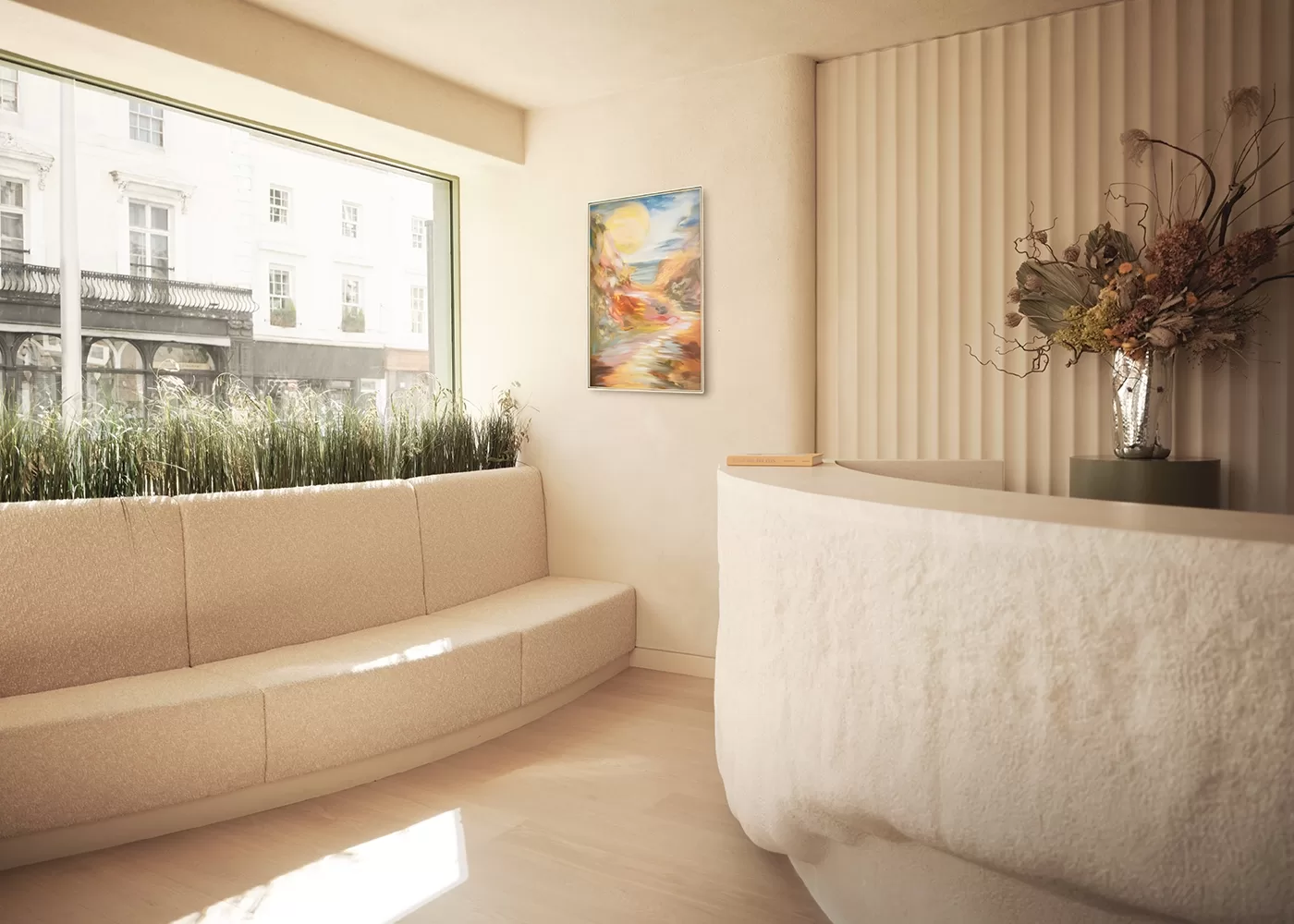A minimalist waiting room with a curved beige sofa, large window, textured white reception desk, and a vibrant abstract painting on the wall. A vase with dried flowers decorates the desk, and sunlight streams through the window.