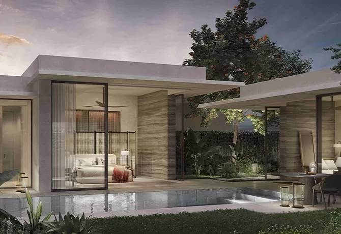 Modern villa with large glass windows overlooking a small pool. The interior bedroom is visible with a cosy bed and nightstand. Outdoor seating is arranged near the pool, surrounded by greenery. The sky shows a hint of sunset at Raffles Sentosa Singapore.