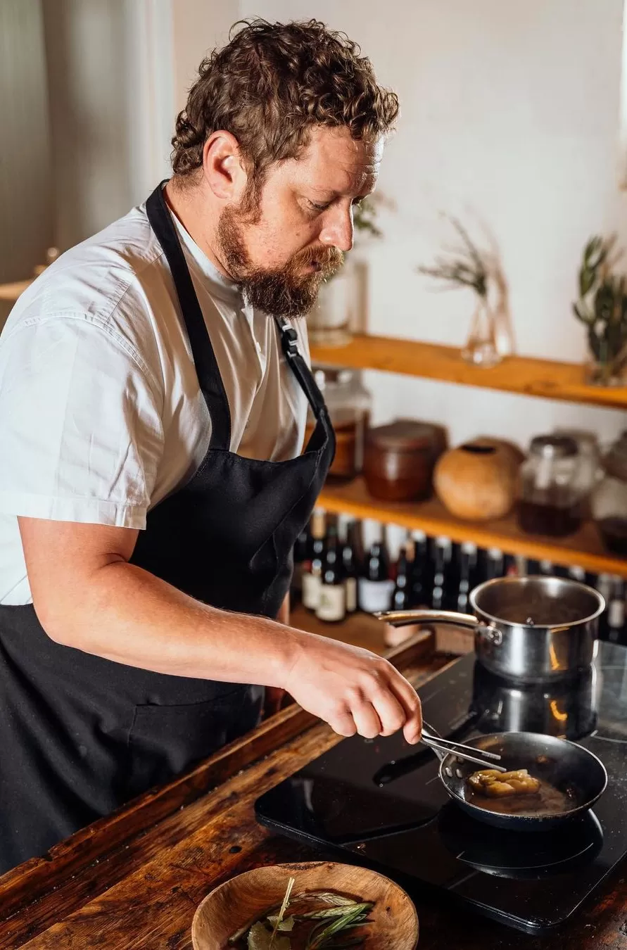 Influential ‘open fire’ chef Niklas Ekstedt in chef uniform cooking in a kitchen on a stove with pans in Norway