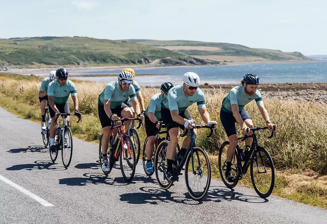 Group of cyclists cycling on road next landscape and sea view on 'led by leaders' cycling exhibition by Le Blanq in Norway