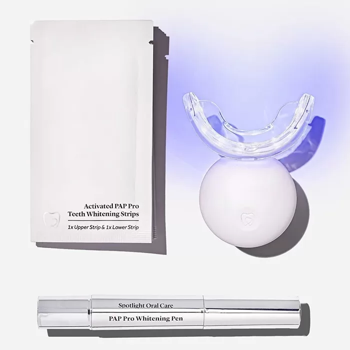A set of teeth whitening products including an activated PAP Pro whitening strip pack, a teeth whitening light device, and a PAP Pro whitening pen, arranged against a light background.