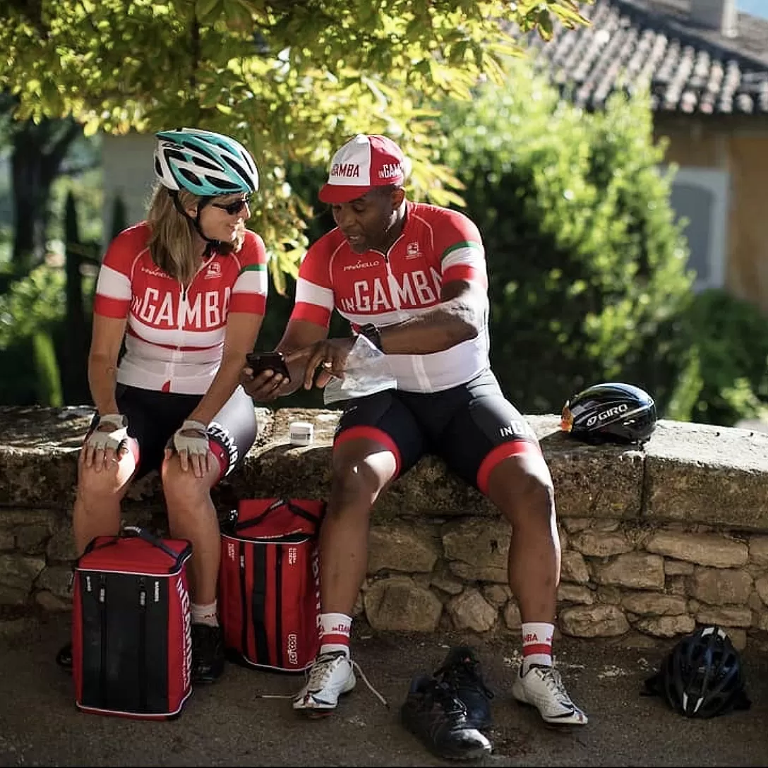 Two people in cycling gear sat on a wall looking at a phone