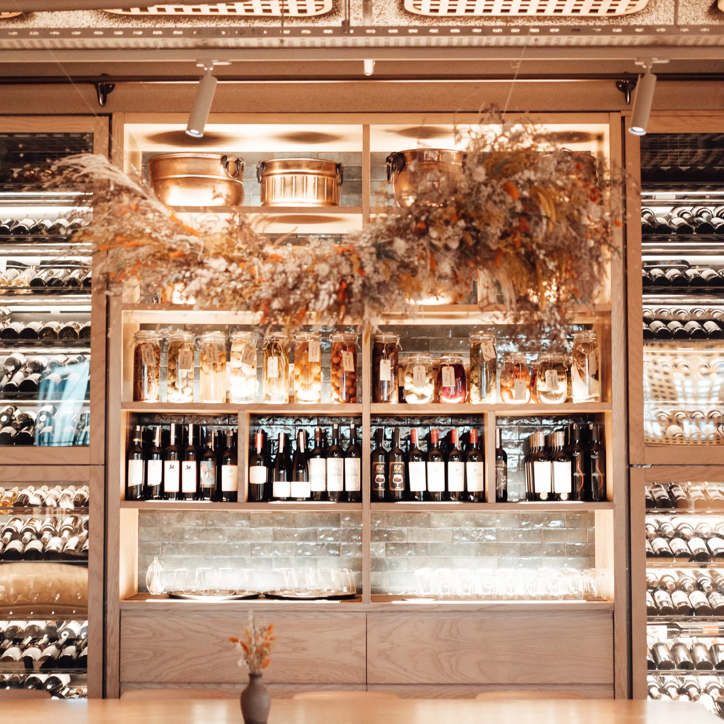 Sehlves stacked with wine bottles and fridge stacked with wine with garland over the door
