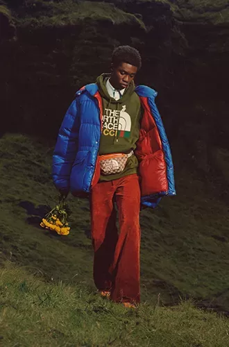 Male model in North Face x Gucci fashion clothing walking down grass catwalk