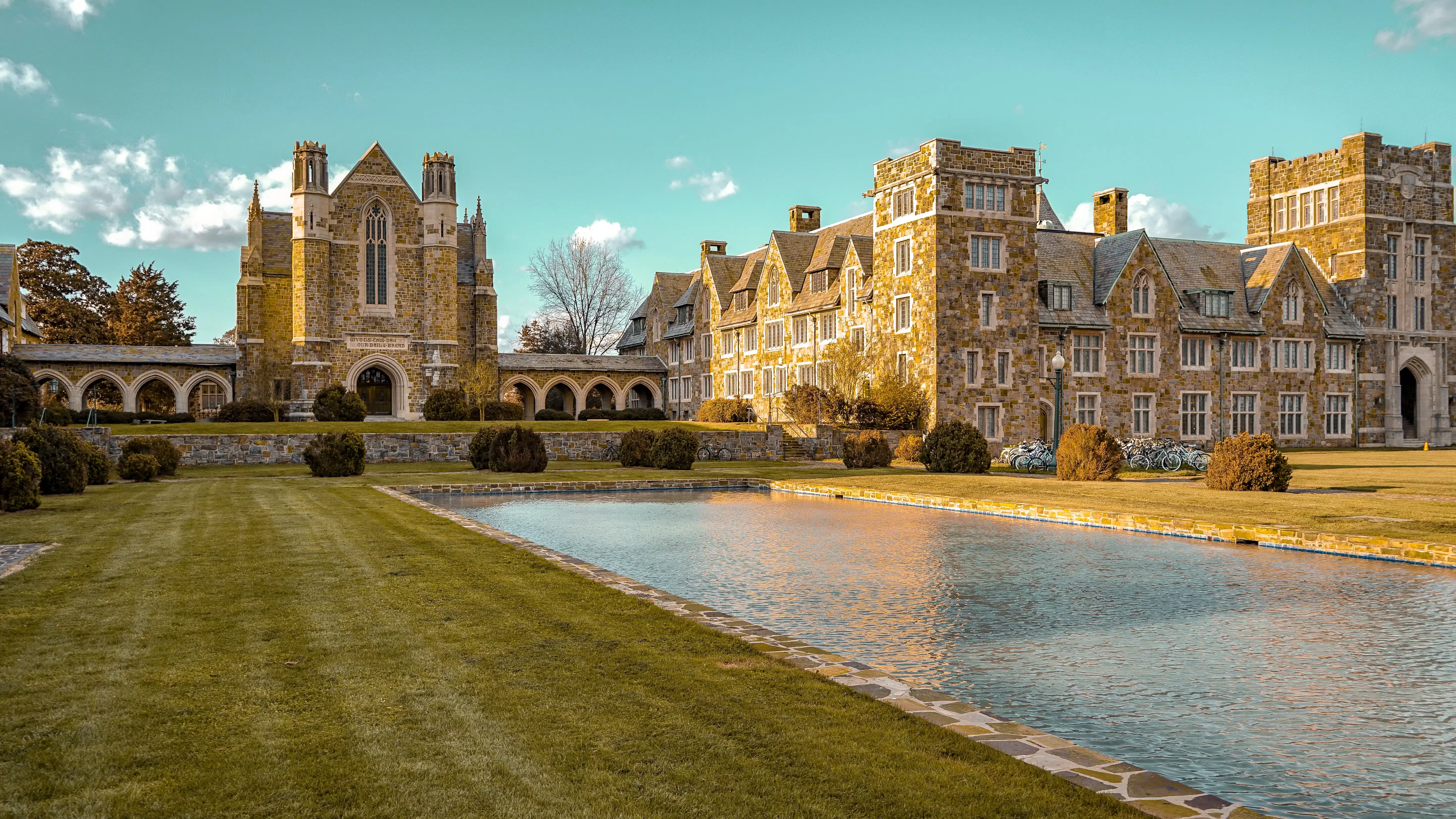 Landscape view of garden and square pool outside of rustic grand building