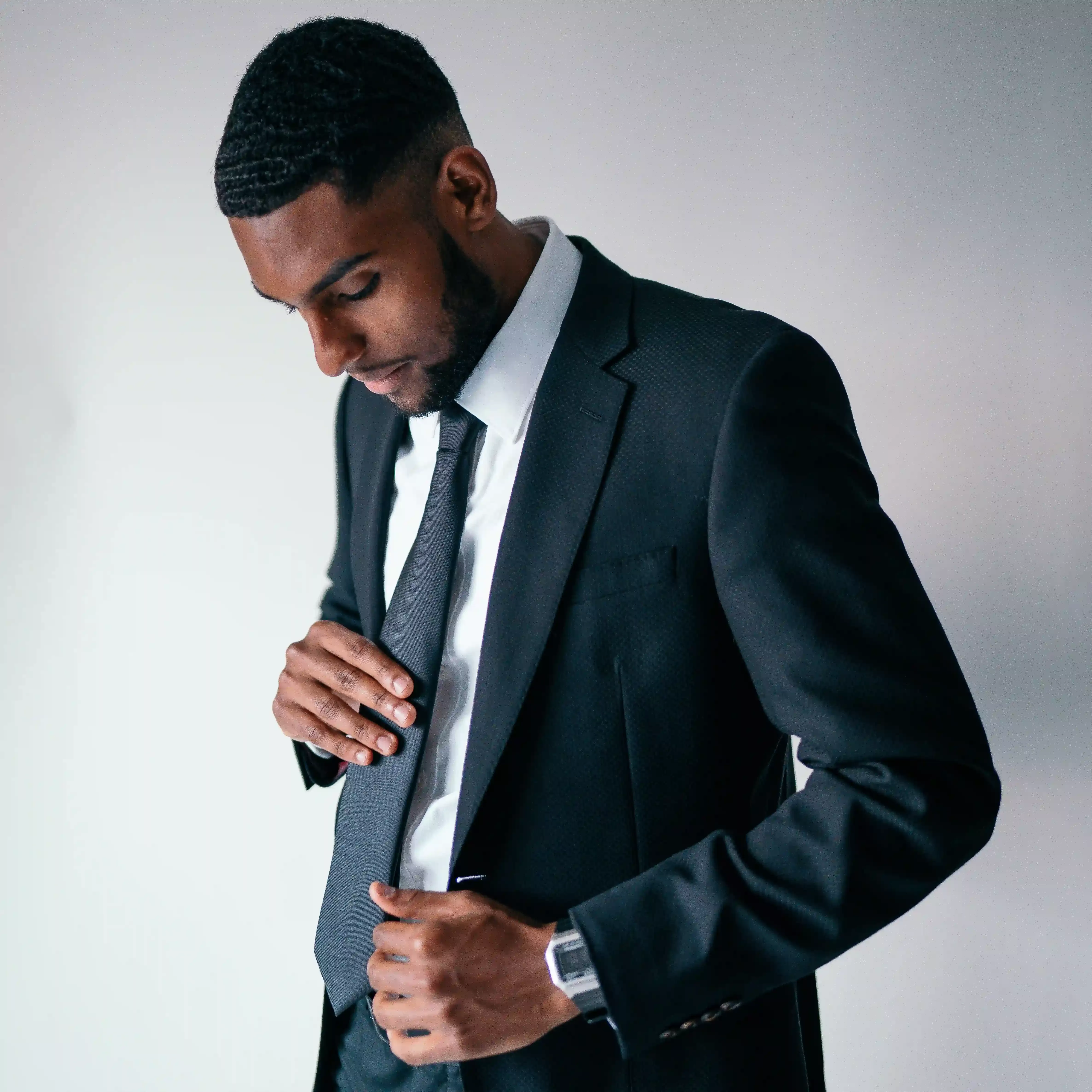 Man in black lounge suit playing with his tie