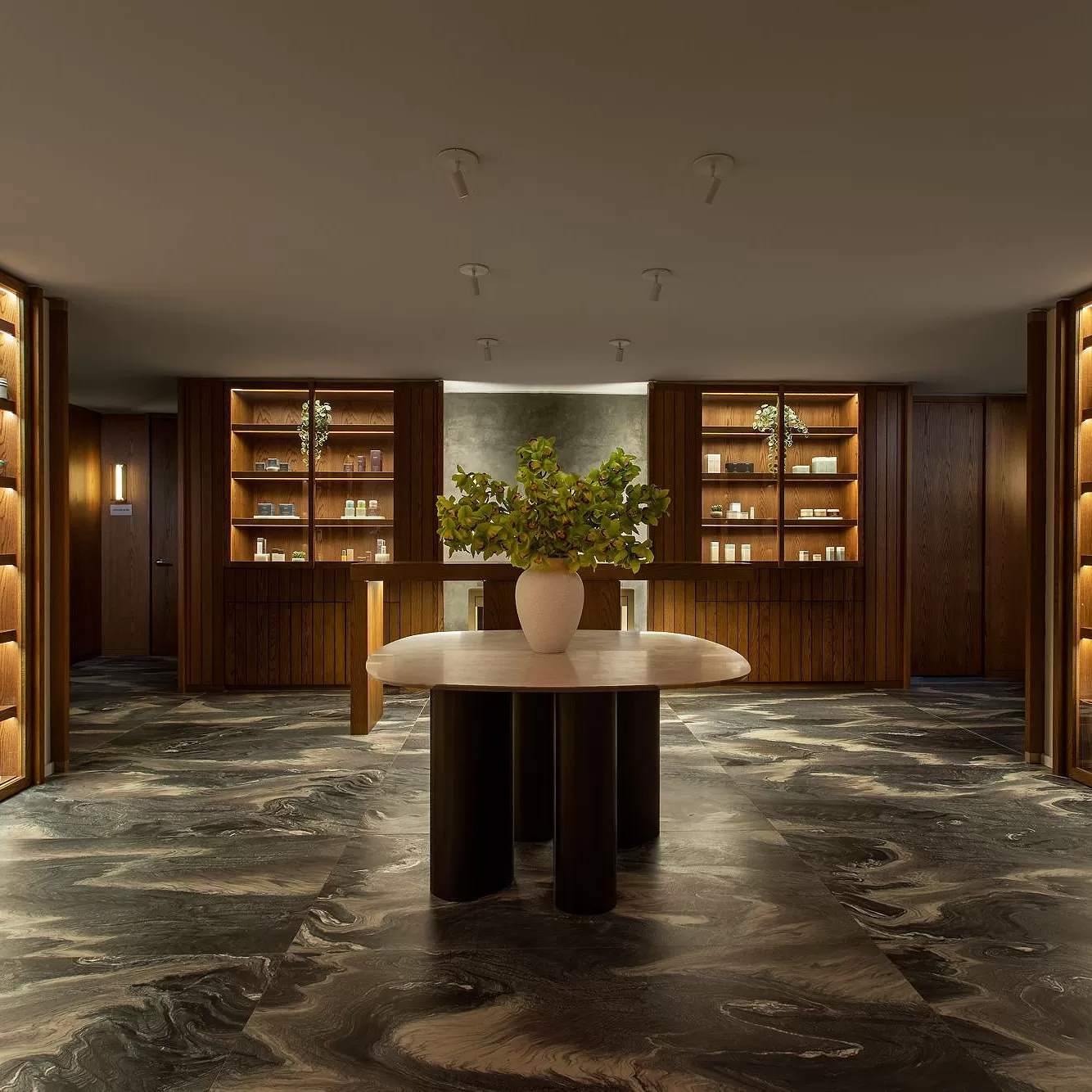 Luxury grand spa lobby interior with marble flooring, centre room table and plant and wooden wall shelving at The Ritz-Carlton New York, NoMad